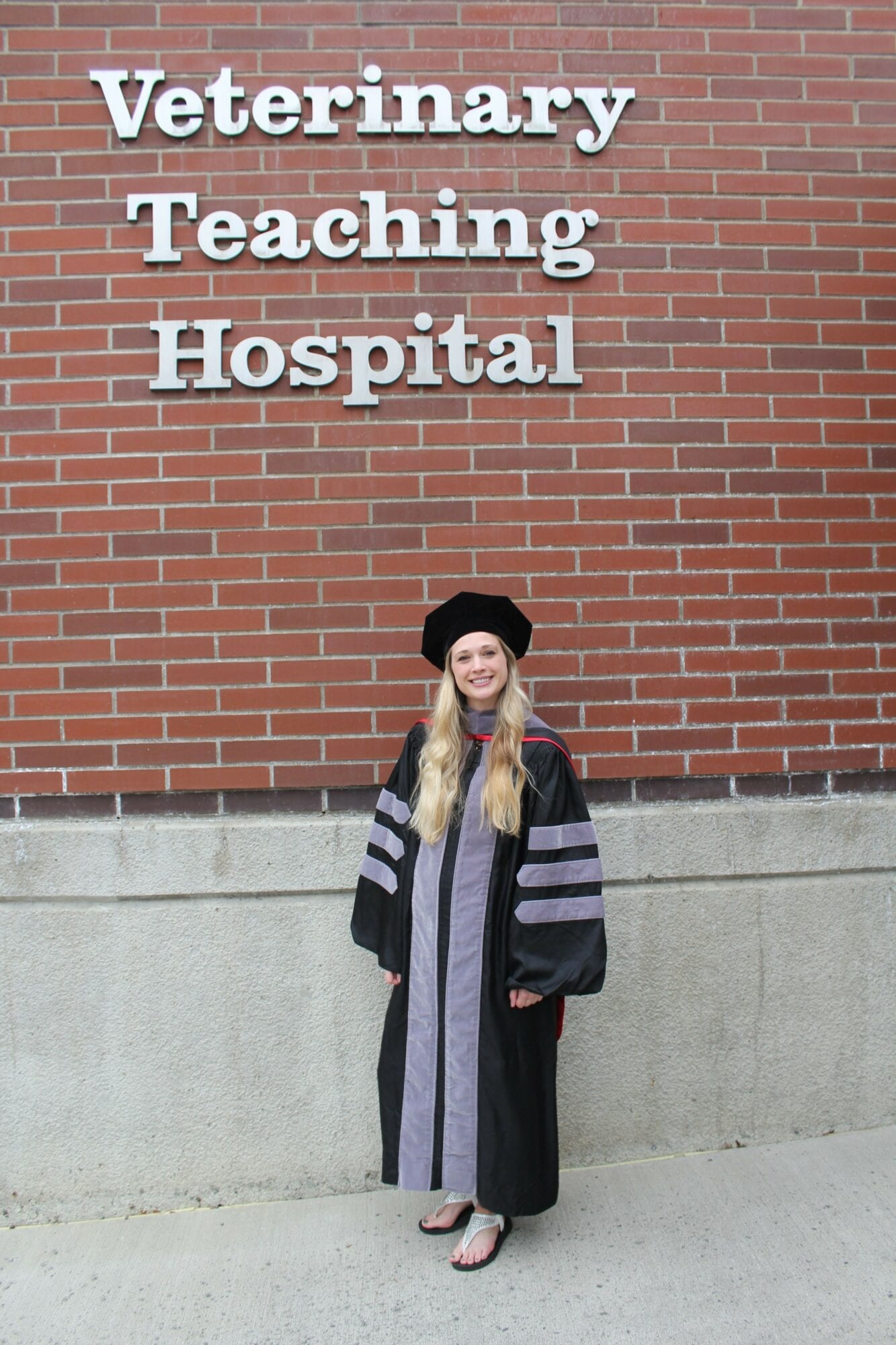 Nicole Sorensen in doctoral regalia at the Washington State University Veterinary Teaching Hospital on graduation day